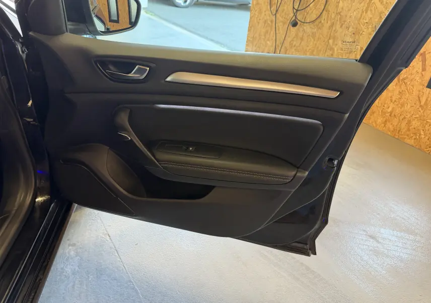 Vue intérieure de la porte avant gauche noire de la Renault Mégane Estate 2024, avec poignée et garniture en cuir.
