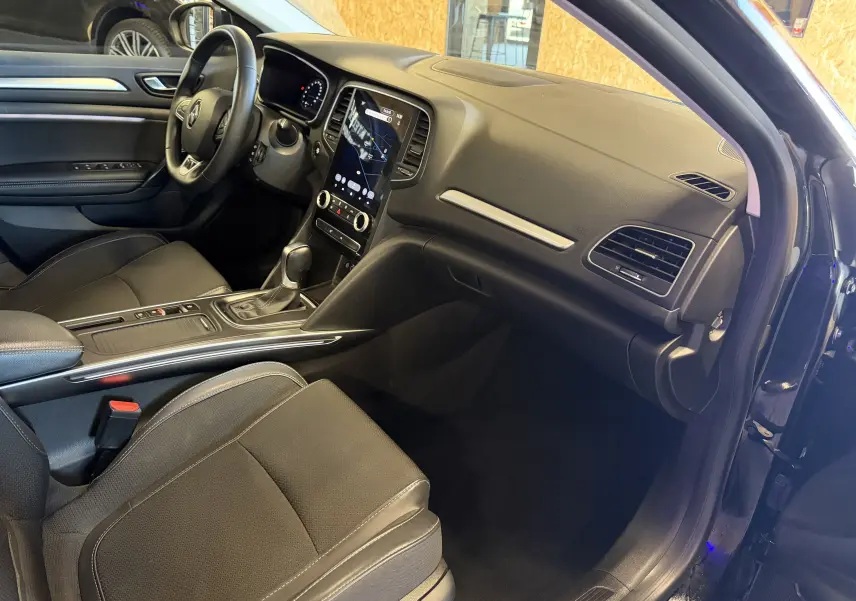 Vue intérieure côté conducteur de la Renault Mégane Estate 2024 noire, avec tableau de bord moderne et écran tactile vertical.