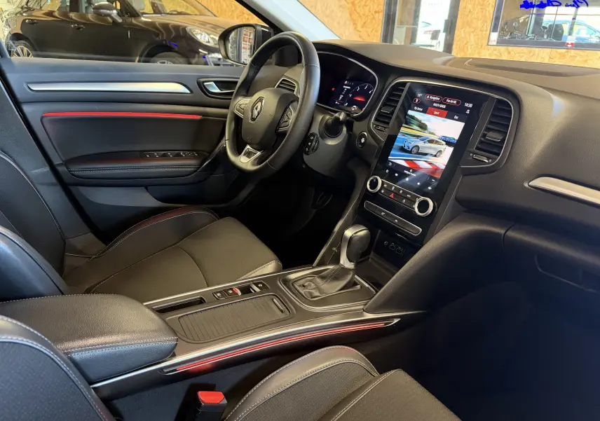 Vue intérieure côté conducteur de la Renault Mégane Estate 2024, avec tableau de bord noir et écran tactile vertical.
