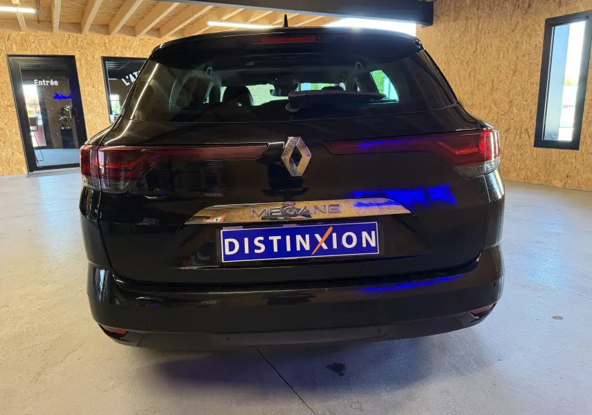 Vue arrière d’une Renault Mégane Estate noire 2024 avec logo et plaque Distinxion dans un garage.