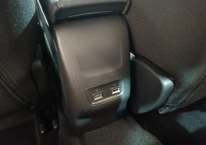 Prise USB double vue en gros plan à l'arrière de la console centrale d'une Peugeot 208 électrique gris clair.