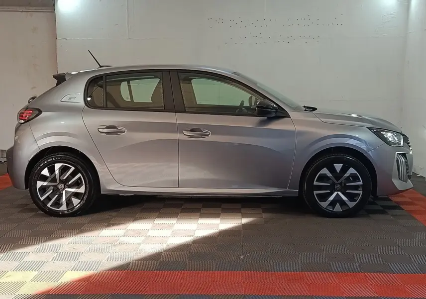 Peugeot 208 électrique gris clair vue de profil côté gauche, avec jantes au design moderne et feux arrière LED.