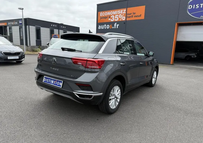 Volkswagen T-Roc gris Indium métal vu de l'arrière droit, avec détails chromés et feux arrière allongés.