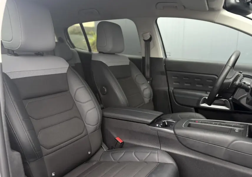 Vue intérieure côté conducteur du Citroën C5 Aircross Hybrid 2024, sièges Advanced Comfort noirs et gris, volant cuir.
