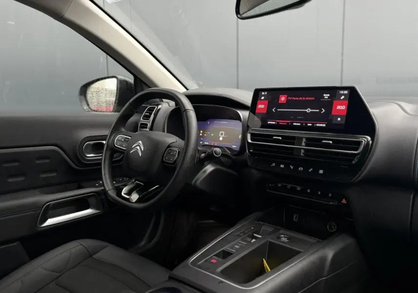 Vue intérieure côté conducteur du Citroën C5 Aircross Hybrid 2024, tableau de bord noir avec écran tactile 10 pouces.