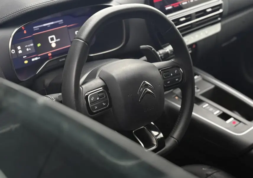 Vue intérieure centrée sur le volant cuir noir et le combiné numérique du Citroën C5 Aircross Hybrid 2024.