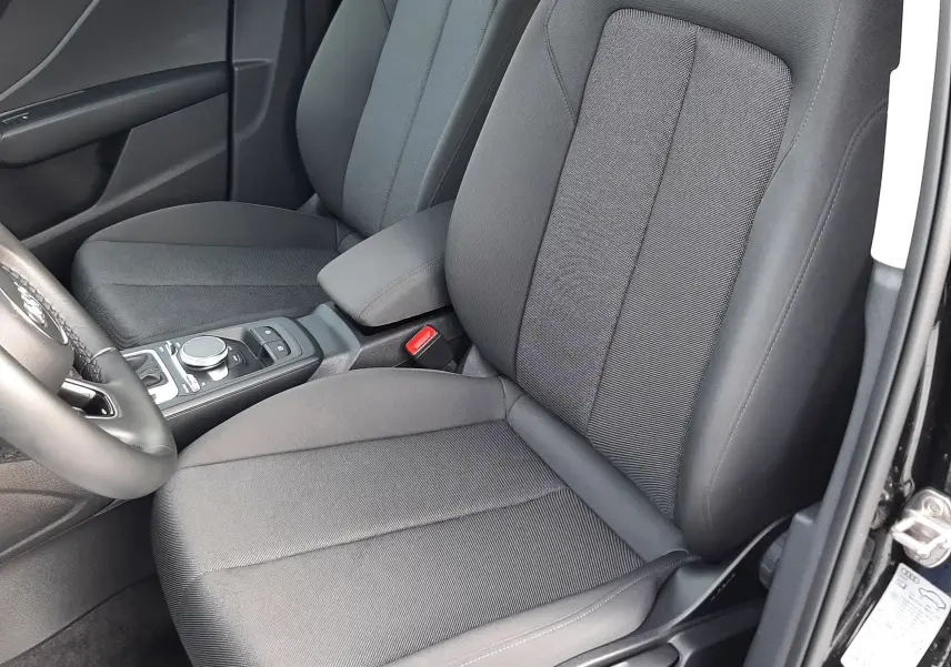 Intérieur avant droit de l'Audi Q2 35 TFSI S-Line 2023 avec sièges tissu gris foncé et console centrale noire.