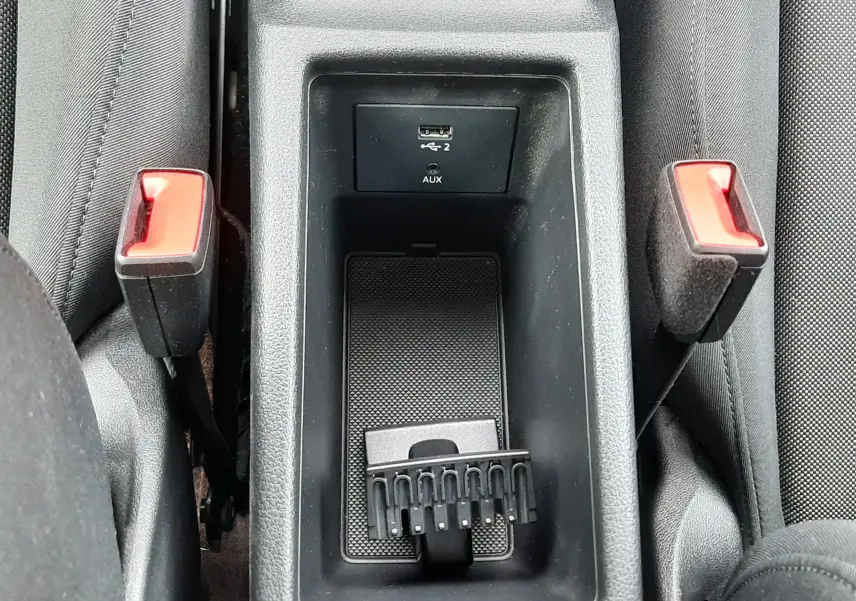 Vue en plongée sur la console centrale noire avec port USB et deux boucles de ceinture dans l'Audi Q2 2023.
