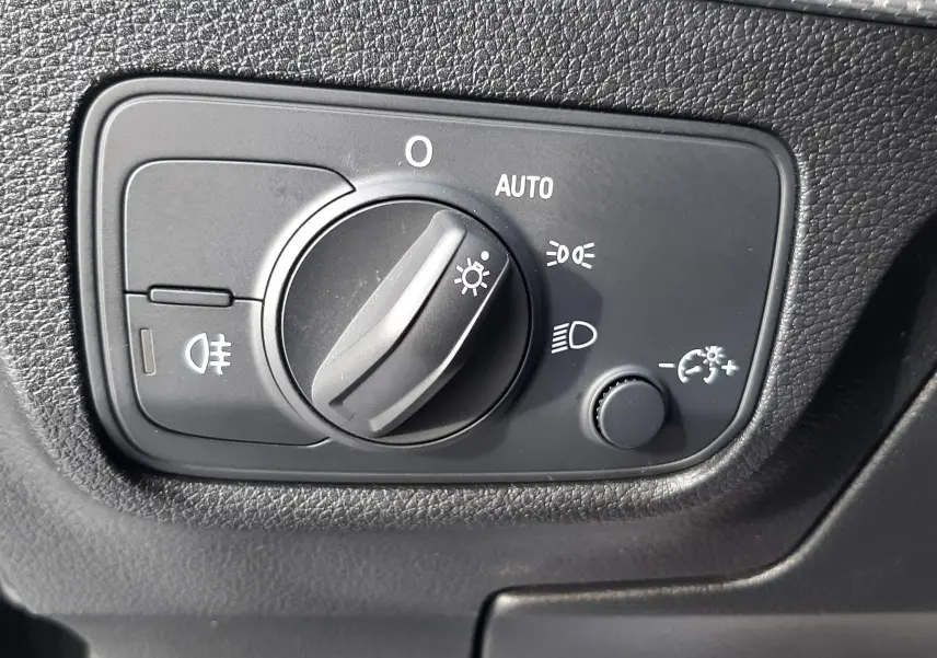 Gros plan sur le commutateur d'éclairage intérieur noir du tableau de bord de l'Audi Q2 35 TFSI S-Line 2023.