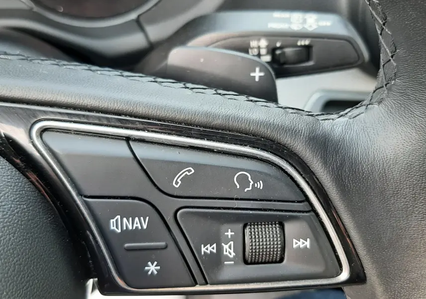 Gros plan sur les commandes au volant à gauche de l'Audi Q2 35 TFSI S-Line 2023, cuir noir et molette de réglage.