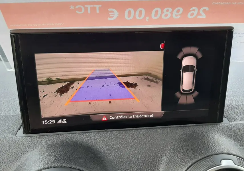 Écran multimédia montrant la caméra de recul et l'aide au stationnement d'un Audi Q2 noir mito metal, intérieur avant.