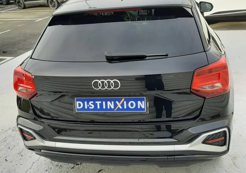 Vue arrière d'un Audi Q2 noir mito metal 2023 avec feux rouges et plaque d'immatriculation Distinxion visible.