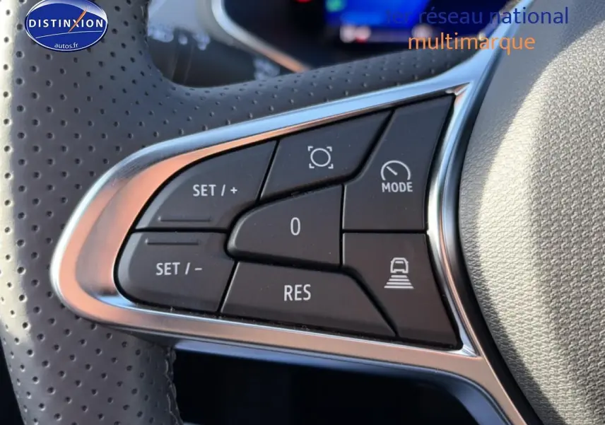 Gros plan sur les commandes du volant perforé gris clair de la Renault Symbioz 2026, boutons de régulateur de vitesse visibles.