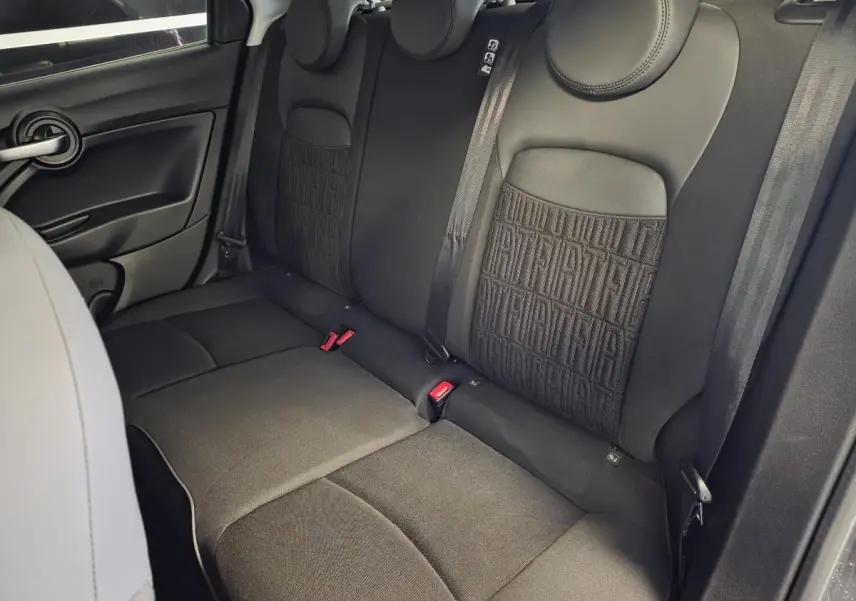 Vue intérieure sur les sièges arrière noirs avec monogramme FIAT du Fiat 500X gris, côté droit visible.