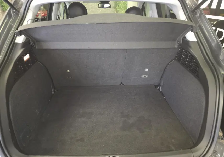 Coffre ouvert vu de l'arrière du Fiat 500X gris, montrant un espace de chargement propre et spacieux.