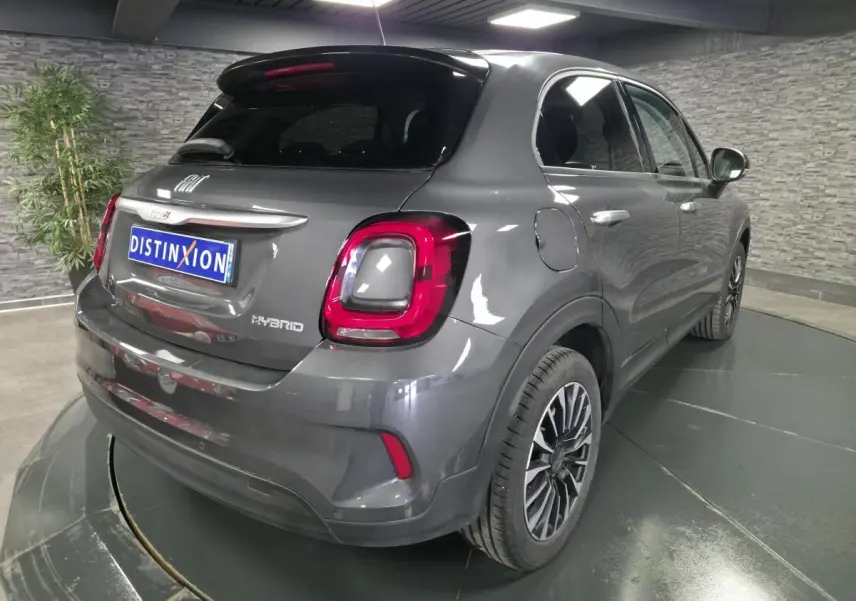 Vue 3/4 arrière droite d'une Fiat 500X gris avec feux arrière LED et jantes alliage 17 pouces dans un showroom.