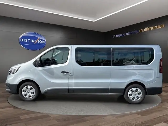 Profil latéral droit d’un Renault Trafic Fourgon gris clair 2022, avec grandes fenêtres et jantes acier.