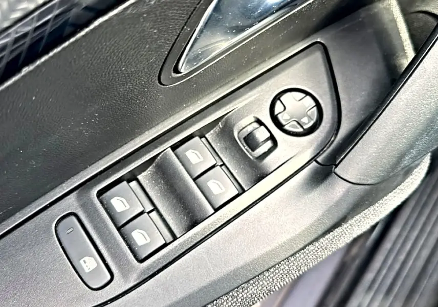 Gros plan sur les commandes de lève-vitres et réglage des rétroviseurs côté conducteur d’un Peugeot 2008 gris.