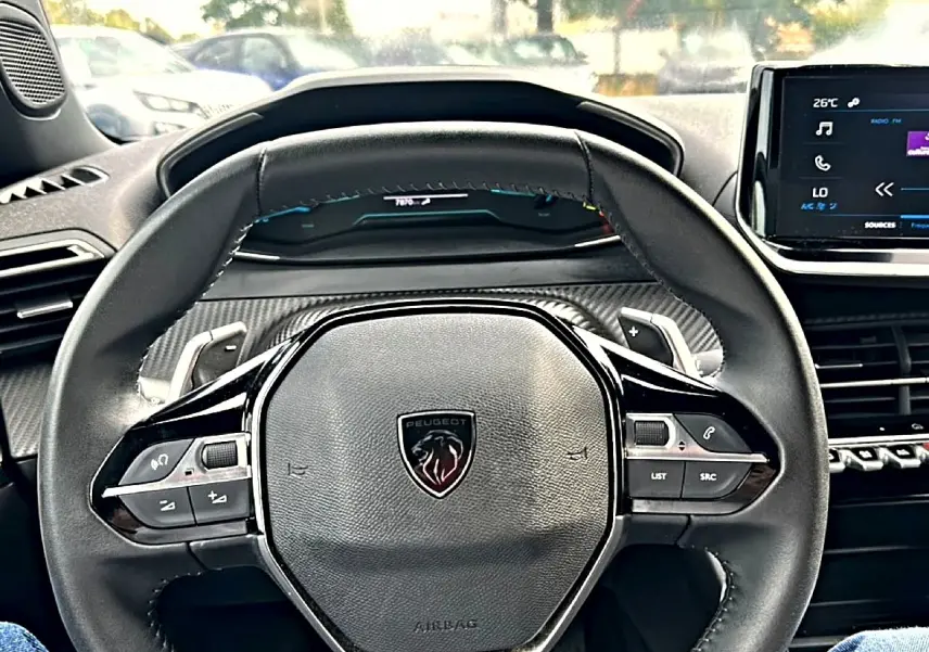 Vue centrée sur le volant multifonction noir du Peugeot 2008 1.2 hybrid 145 style avec tableau de bord et écran tactile.