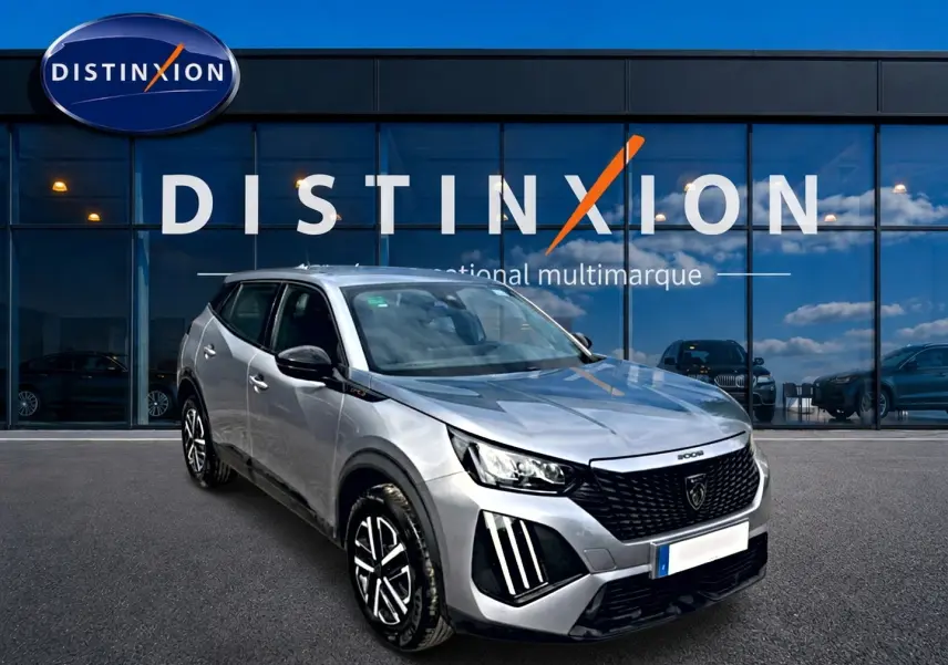 Peugeot 2008 gris en 3/4 avant droit, avec calandre noire distinctive et phares LED verticaux.