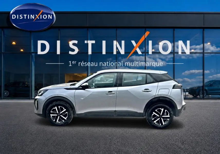 Profil droit d’un Peugeot 2008 gris 2025 avec toit noir et jantes modernes devant une vitrine Distinxion.