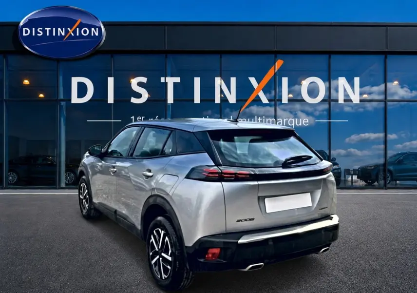 Peugeot 2008 gris 3/4 arrière droit, avec feux arrière LED et becquet, stationné devant une vitrine Distinxion.