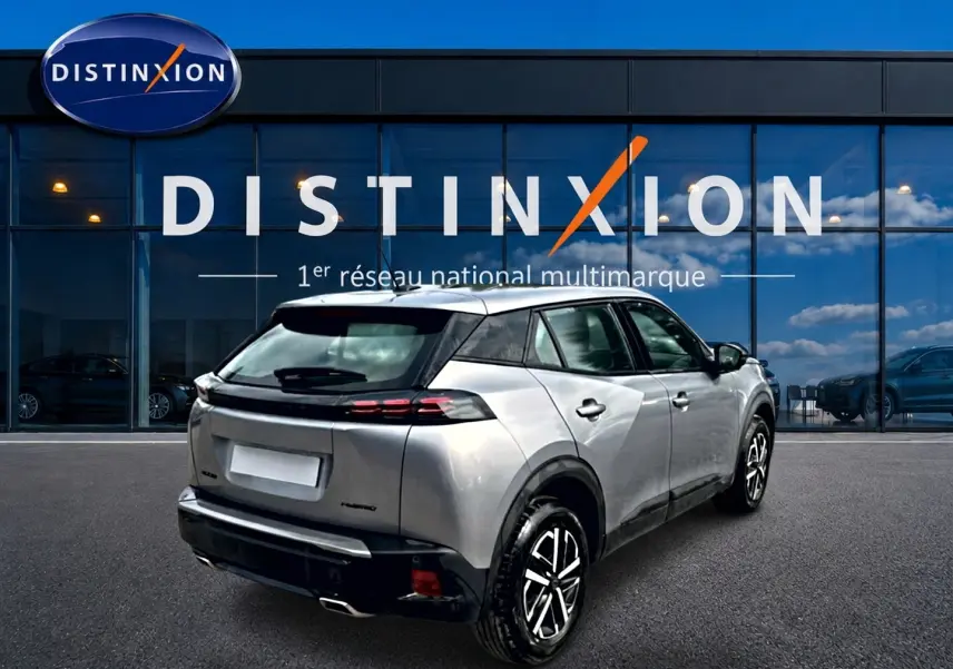 Vue 3/4 arrière droite d'un Peugeot 2008 gris 2025 avec toit noir et feux arrière LED, devant une vitrine Distinxion.