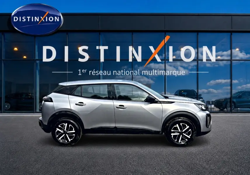Peugeot 2008 gris en profil droit, avec jantes noires et toit noir, devant une vitrine Distinxion.