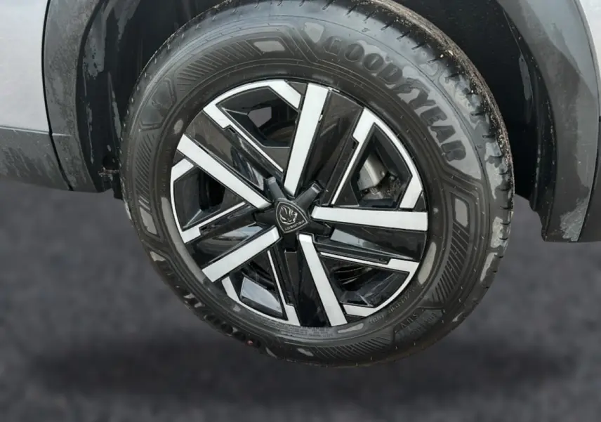 Gros plan sur la roue avant droite du Peugeot 2008 gris, mettant en valeur la jante noire et argentée au design moderne.