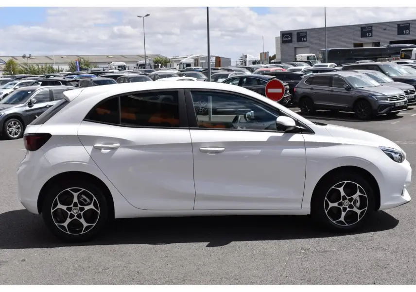 Vue latérale droite d'une MG3 blanche 2026 avec jantes alliage et vitres surteintées en extérieur parking.