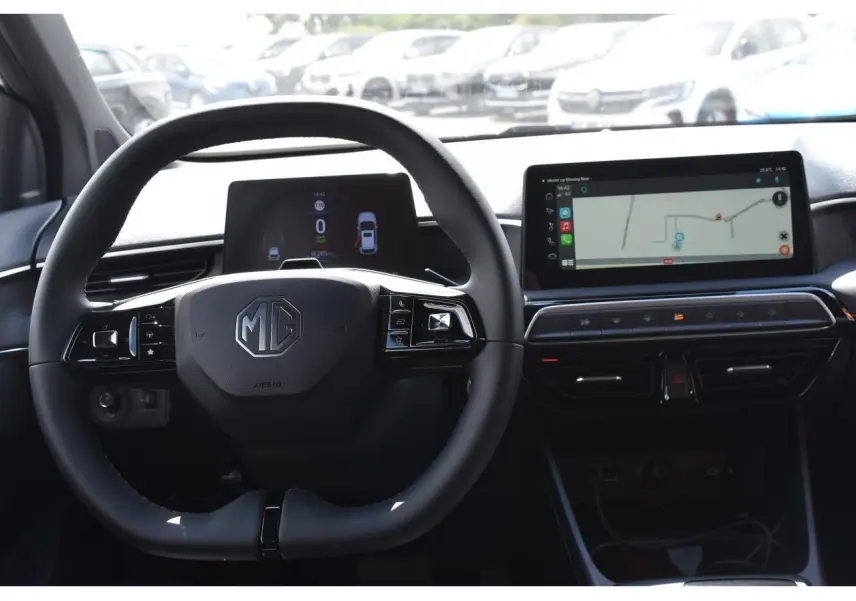 Vue intérieure centrée sur le volant MG avec tableau de bord numérique et écran tactile affichant la navigation.