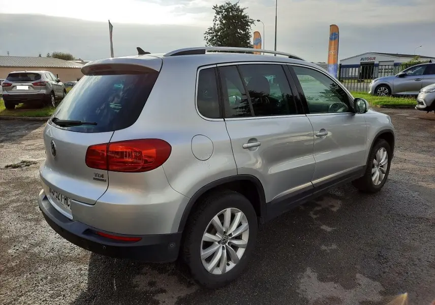 Volkswagen Tiguan 2.0 TDI gris argent vu en 3/4 arrière droit, avec feux arrière rouges et jantes alliage 17 pouces.