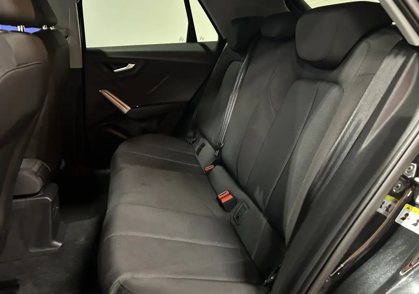 Vue intérieure côté droit des sièges arrière en tissu noir d'un Audi Q2 35 TFSI S-Line 2023 avec porte ouverte.