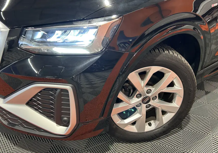 Gros plan sur l'avant droit noir métal d'un Audi Q2 35 TFSI S-Line avec phares LED et jante alliage cinq branches.