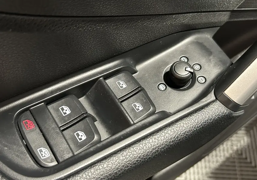 Gros plan sur la plaque de seuil de porte éclairée avec logo S de l'Audi Q2 noir métal, côté conducteur intérieur.