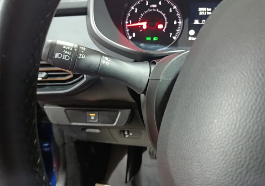 Gros plan sur le volant et la commande des phares d'une Dacia Sandero Extreme+ TCe 110 2024, intérieur noir.