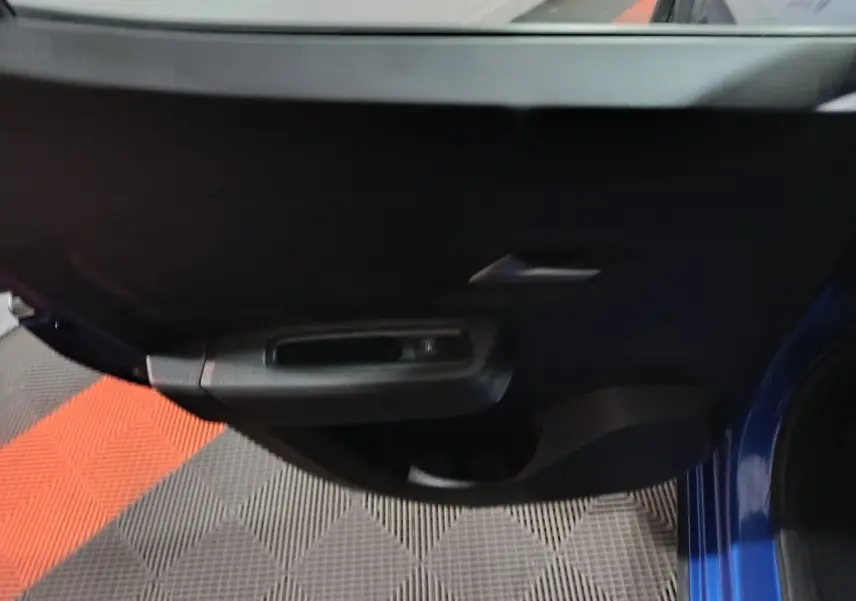 Vue rapprochée de la porte avant gauche bleu de la Dacia Sandero 2024, mettant en valeur la poignée intérieure noire.