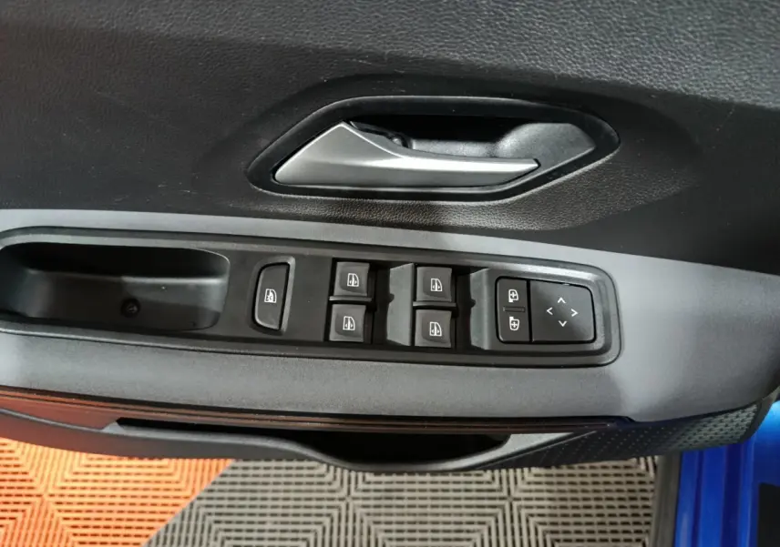 Vue rapprochée de la porte côté conducteur de la Dacia Sandero Extreme+ bleu, montrant les commandes des vitres et rétroviseurs.