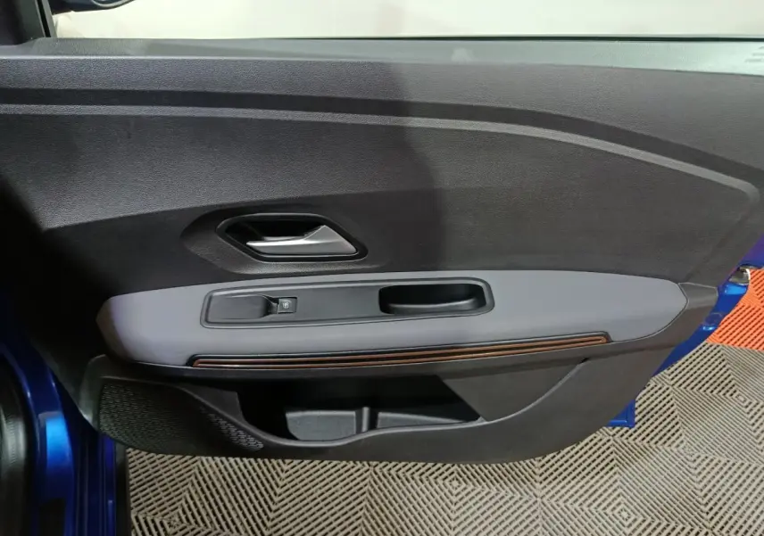 Vue rapprochée de la porte avant gauche bleue de la Dacia Sandero 2024, avec commande de vitre et poignée intérieure.