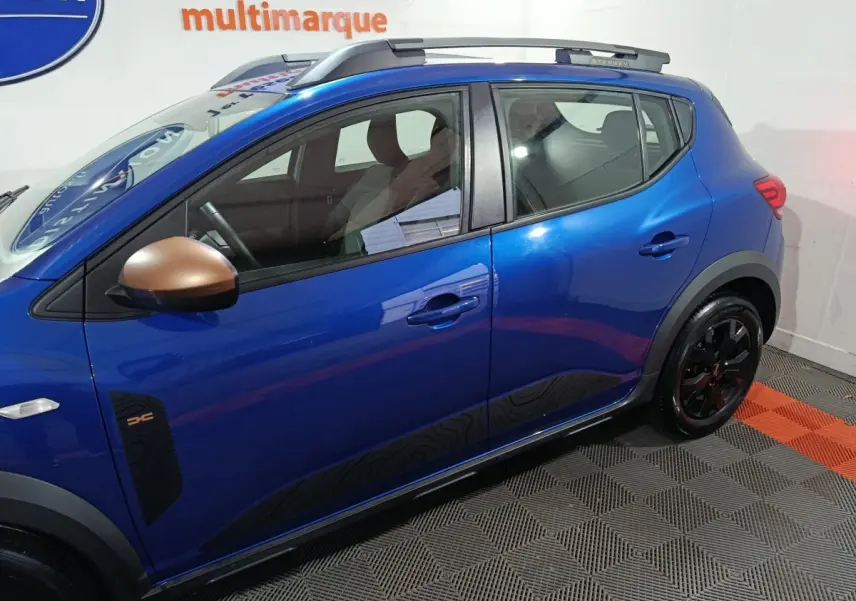 Vue de profil côté gauche d'une Dacia Sandero Extreme+ bleu avec rétroviseurs bronze et jantes noires.