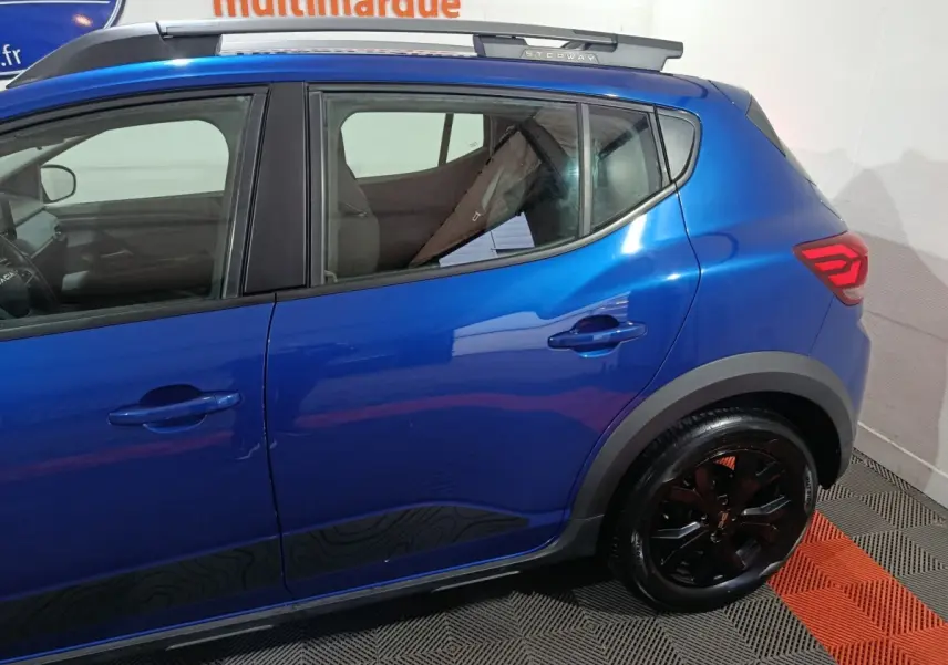Vue latérale droite d'une Dacia Sandero Extreme+ bleu 2024 avec jantes noires et badge Stepway sur le toit.