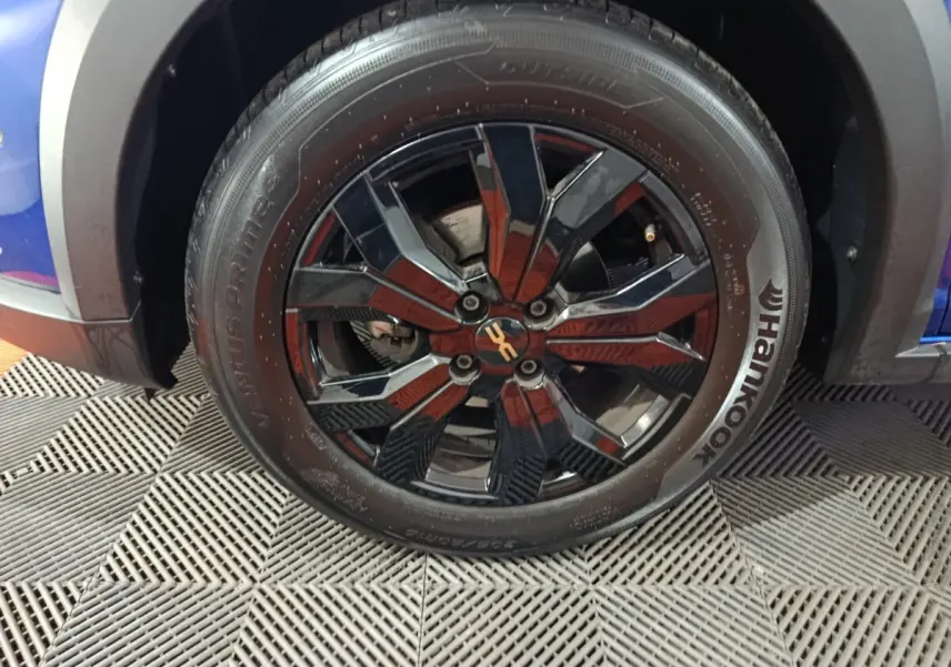 Gros plan sur la roue avant gauche d'une Dacia Sandero Extreme+ bleu 2024 avec jante noire brillante et pneu Hankook.