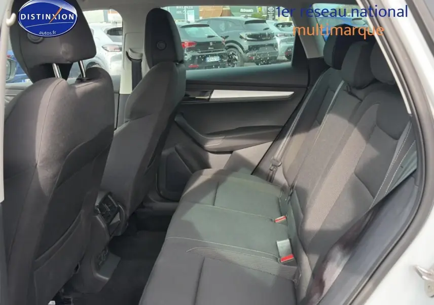 Vue latérale intérieure des sièges arrière noirs du Skoda Karoq blanc glacial, avec accoudoirs et habillage sombre.