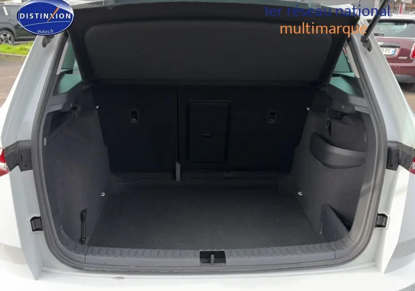 Coffre ouvert vu de l'arrière d'un Skoda Karoq blanc glacial, montrant un espace de rangement spacieux et noir.