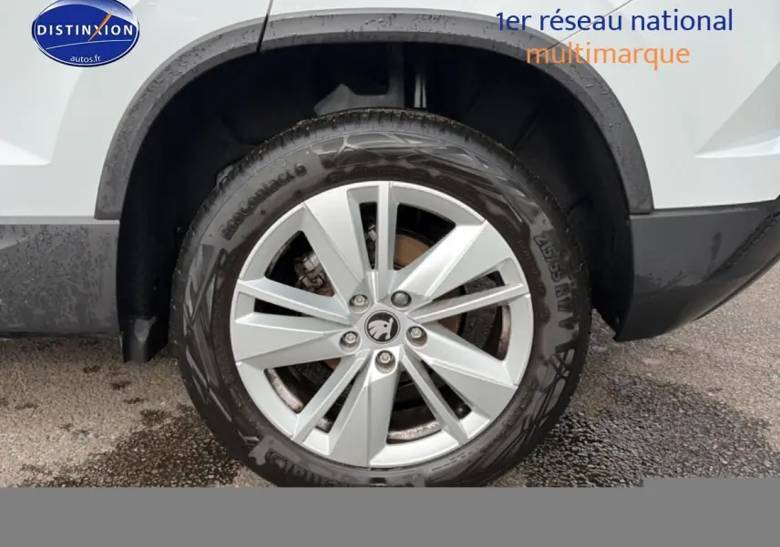 Gros plan sur la roue avant droite d’un Skoda Karoq blanc glacial avec jante alu multibranches.