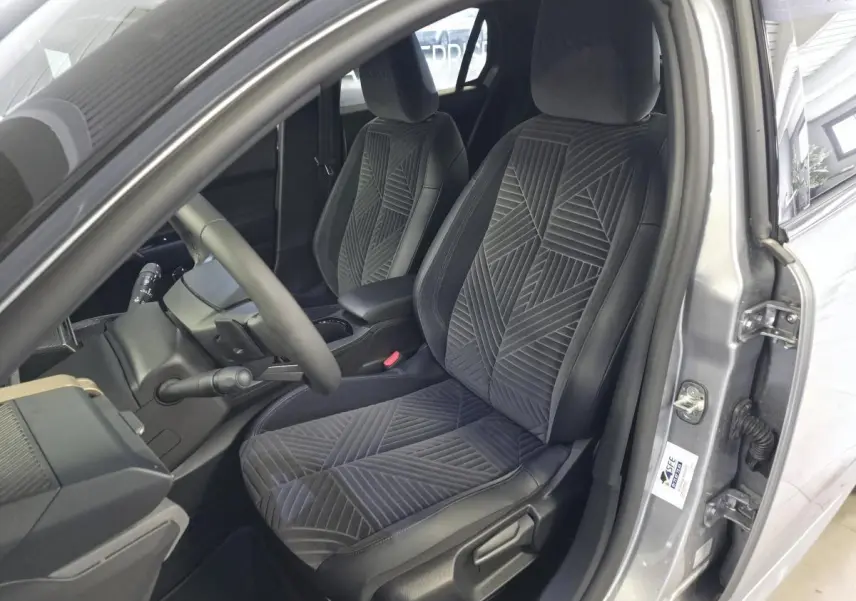 Vue intérieure côté conducteur de la Lancia Ypsilon gris, avec sellerie velours gris anthracite et volant sport.