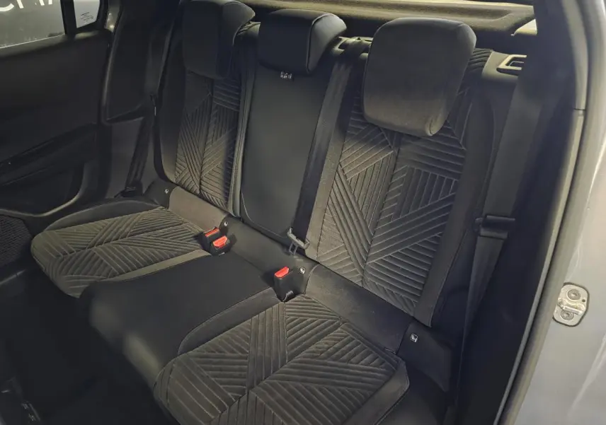 Vue intérieure arrière des sièges en velours gris anthracite de la Lancia Ypsilon 2025, avec ceinture de sécurité et portière ouverte.