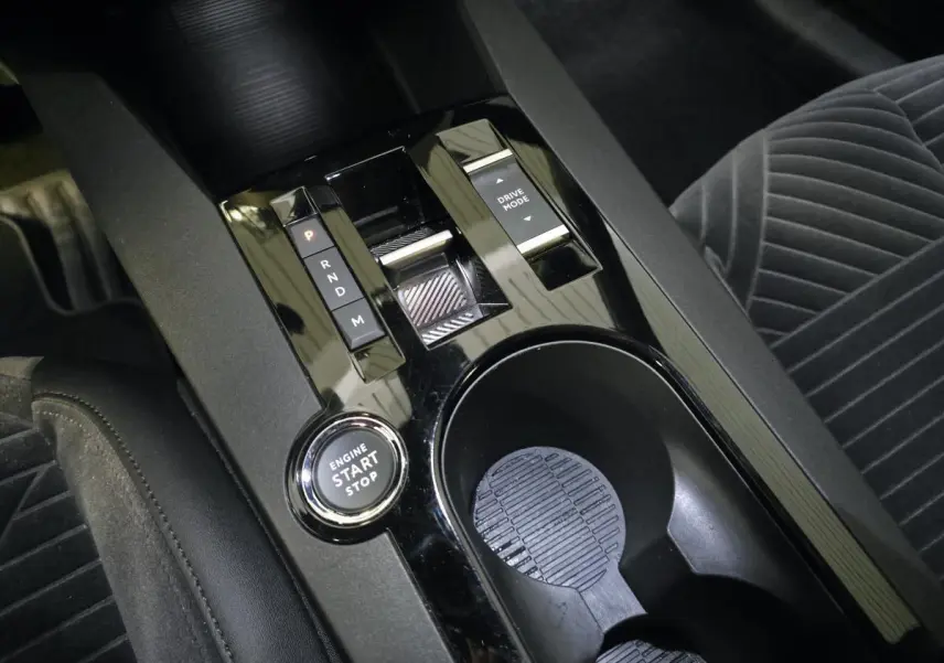 Vue rapprochée de la console centrale noire brillante avec bouton start/stop et levier de boîte automatique sur Lancia Ypsilon gris.