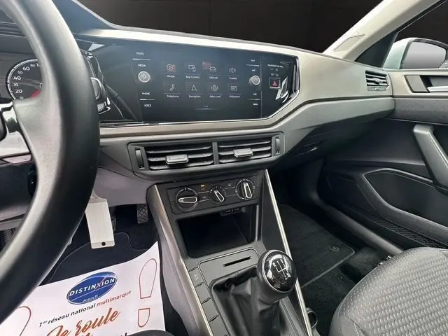 Vue intérieure centrée sur la console centrale et le levier de vitesse manuel d'une Volkswagen Polo gris clair de 2021.