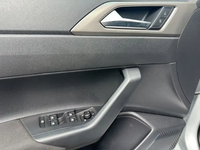 Détail de la porte côté conducteur d'une Volkswagen Polo gris clair 2021, avec commandes électriques et poignée noire.